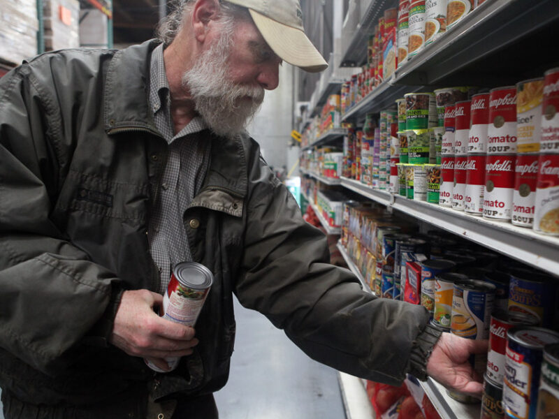 File photo: San Francisco Food Bank volunteer Jim Caddick stocks shelves with soup in 2012.