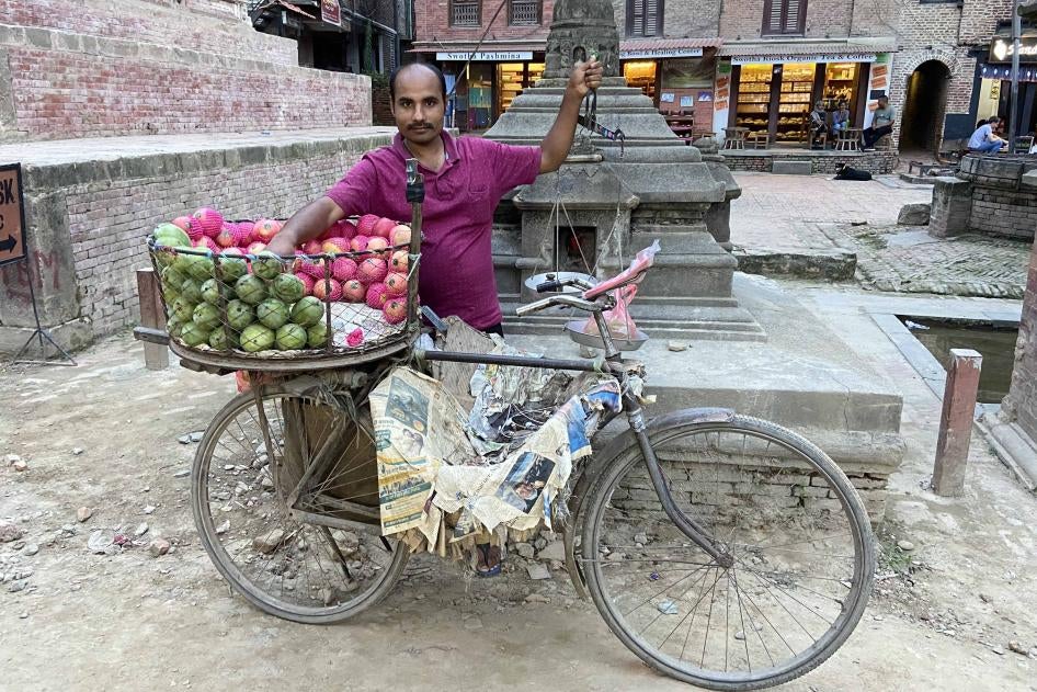 A man poses for a photo with his fruit cart
