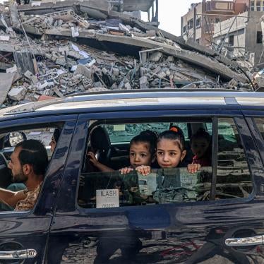 A family in a car drives passed destroyed buildings
