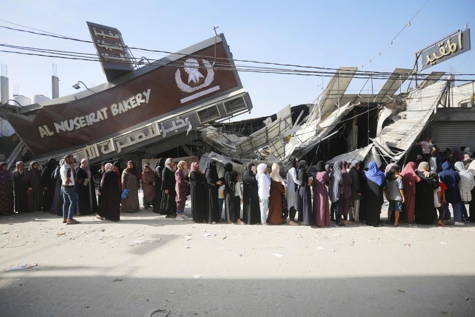 People line up for bread at a partially collapsed but still operational bakehouse in Nuseirat refugee camp in Deir al Balah, Gaza, November 4, 2023.