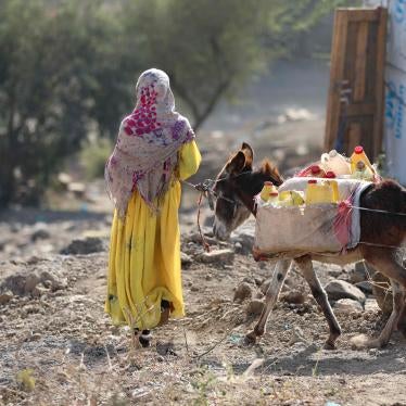 A girl walks with a donkey carrying water containers