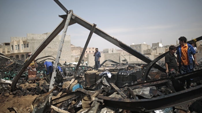 Workers salvage oil canisters from the wreckage of a store hit by Saudi-led airstrikes in Sanaa, Yemen, July 2, 2020.