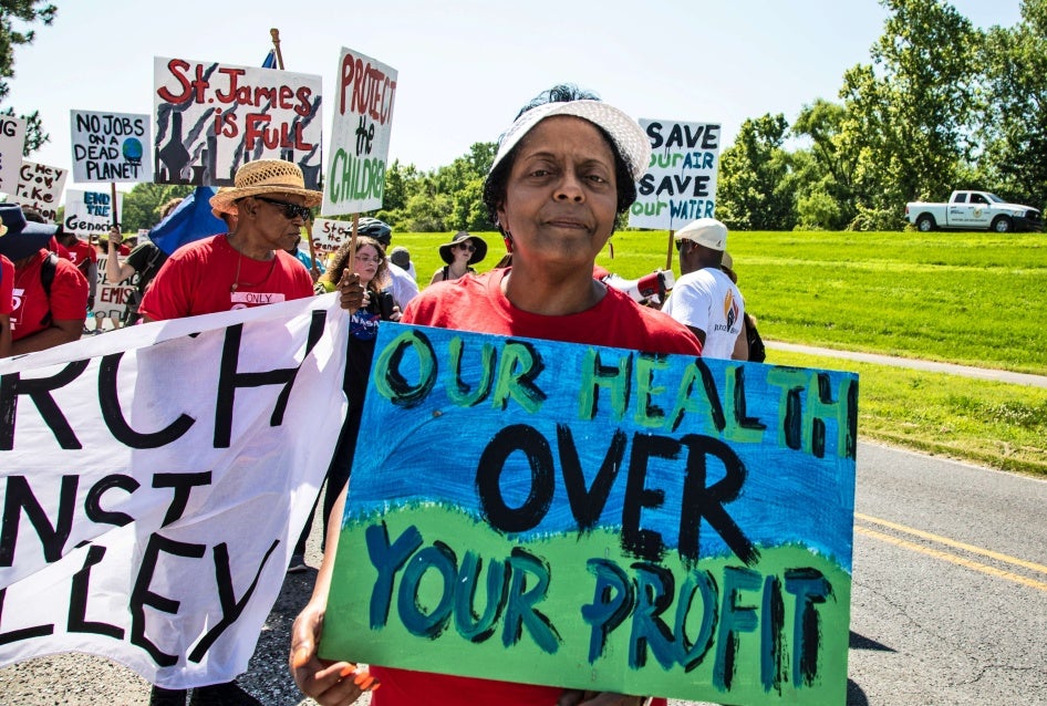 A woman holds a protest sign that says "Our Health Over Your Profit"