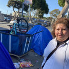 Aurelia Ramirez walks by tents and debris along Folsom Street.