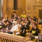 People cheering and waving hands in the audience at a Board of Supervisors meeting