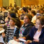 Homeless migrant families and others sit in City Hall Chambers during a meeting.