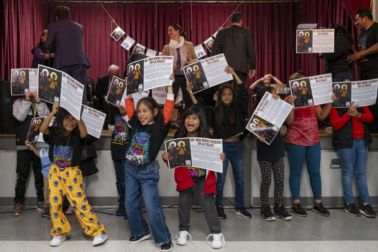 Laughing children hold signs at community event.