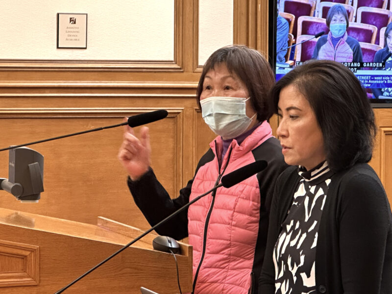 At a City Hall meeting in San Francisco, an interpreter helps a resident make a public comment.