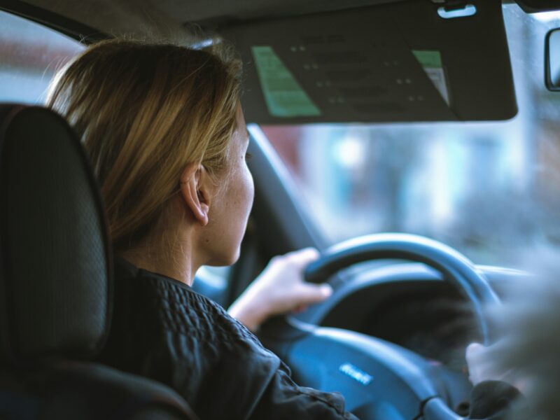 A woman sitting in a car, behind the steering wheel.