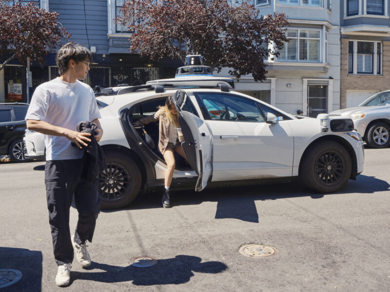 Passengers disembark a Waymo vehicle.