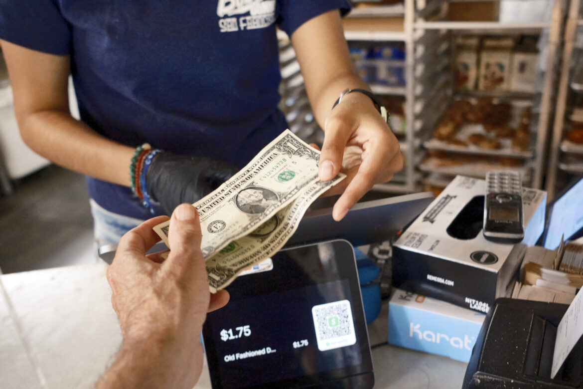 An employee at a local business in San Francisco gives change during a transaction.