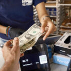 An employee at a local business in San Francisco gives change during a transaction.