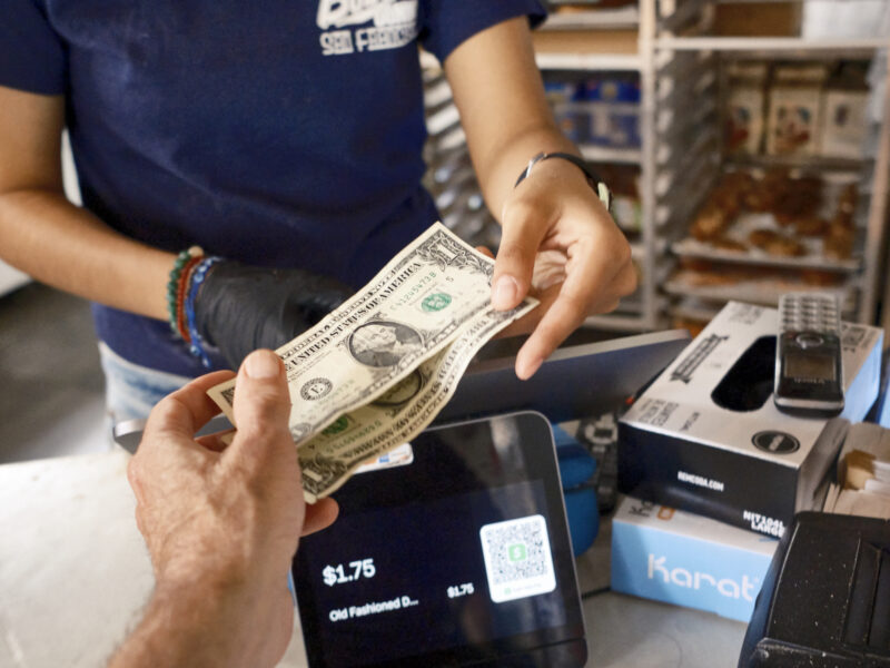 An employee at a local business in San Francisco gives change during a transaction.