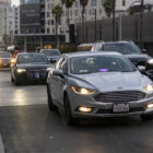 A car with a Lyft sign drives along a city street.